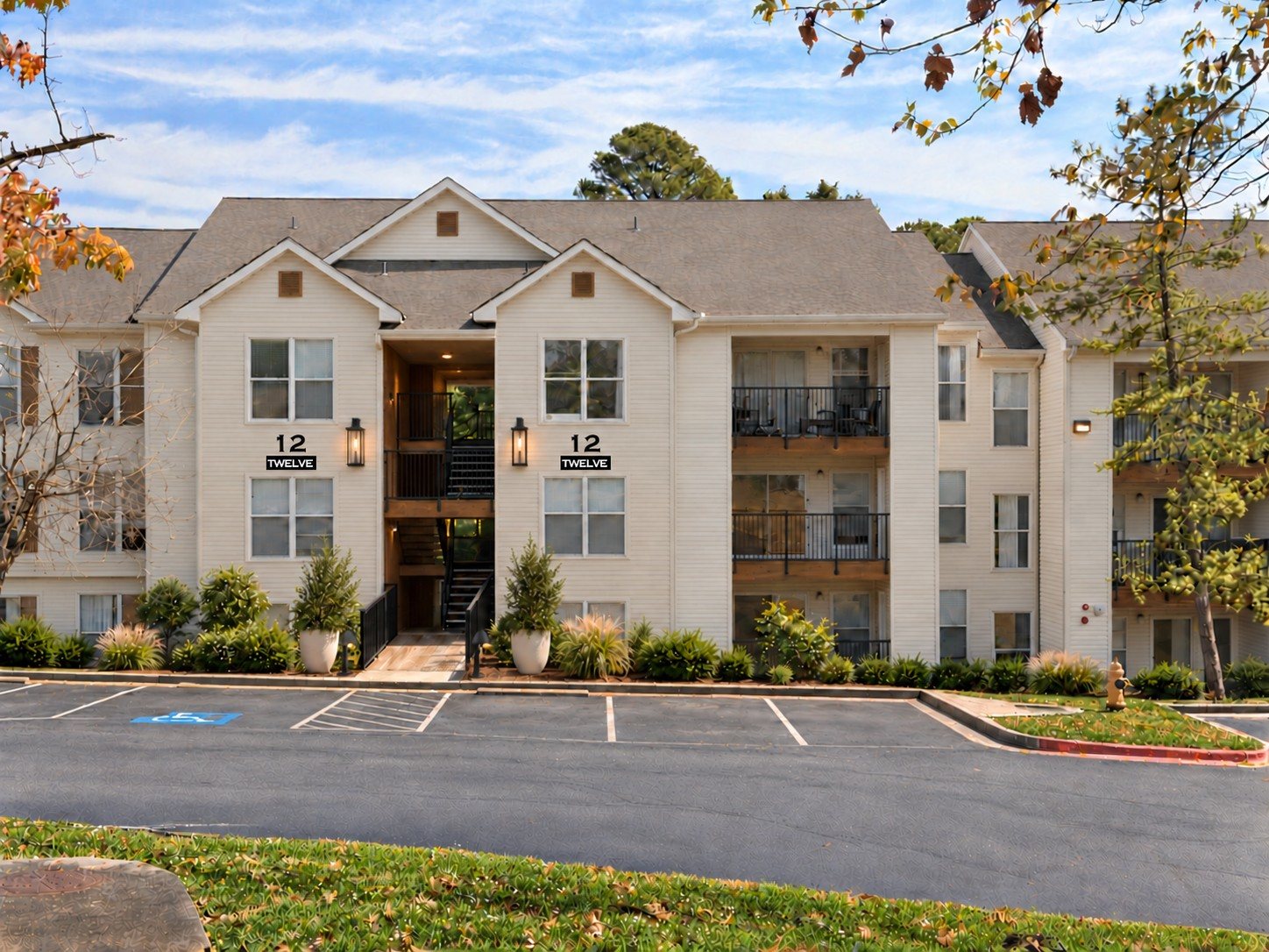 After: a residential building with refreshed ivory facade, black accents, sconces and planting