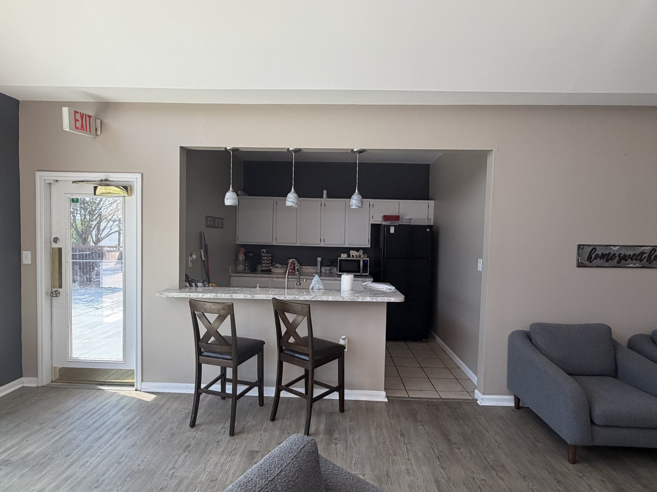 Before: a basic kitchenette with black appliances and wooden stools