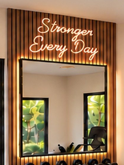 Detail: a neon sign reading Stronger Every Day over a slatted wood wall