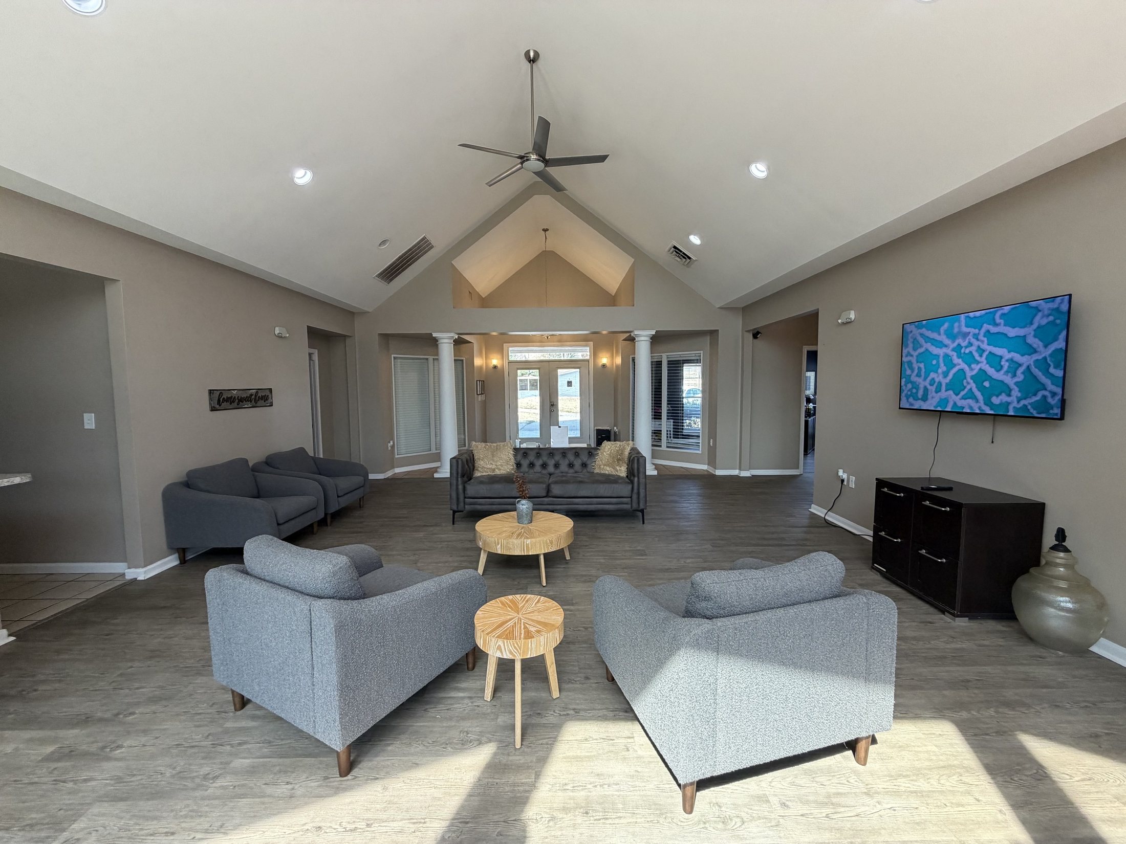 Before: the existing lounge with grey furniture and a wall mounted TV