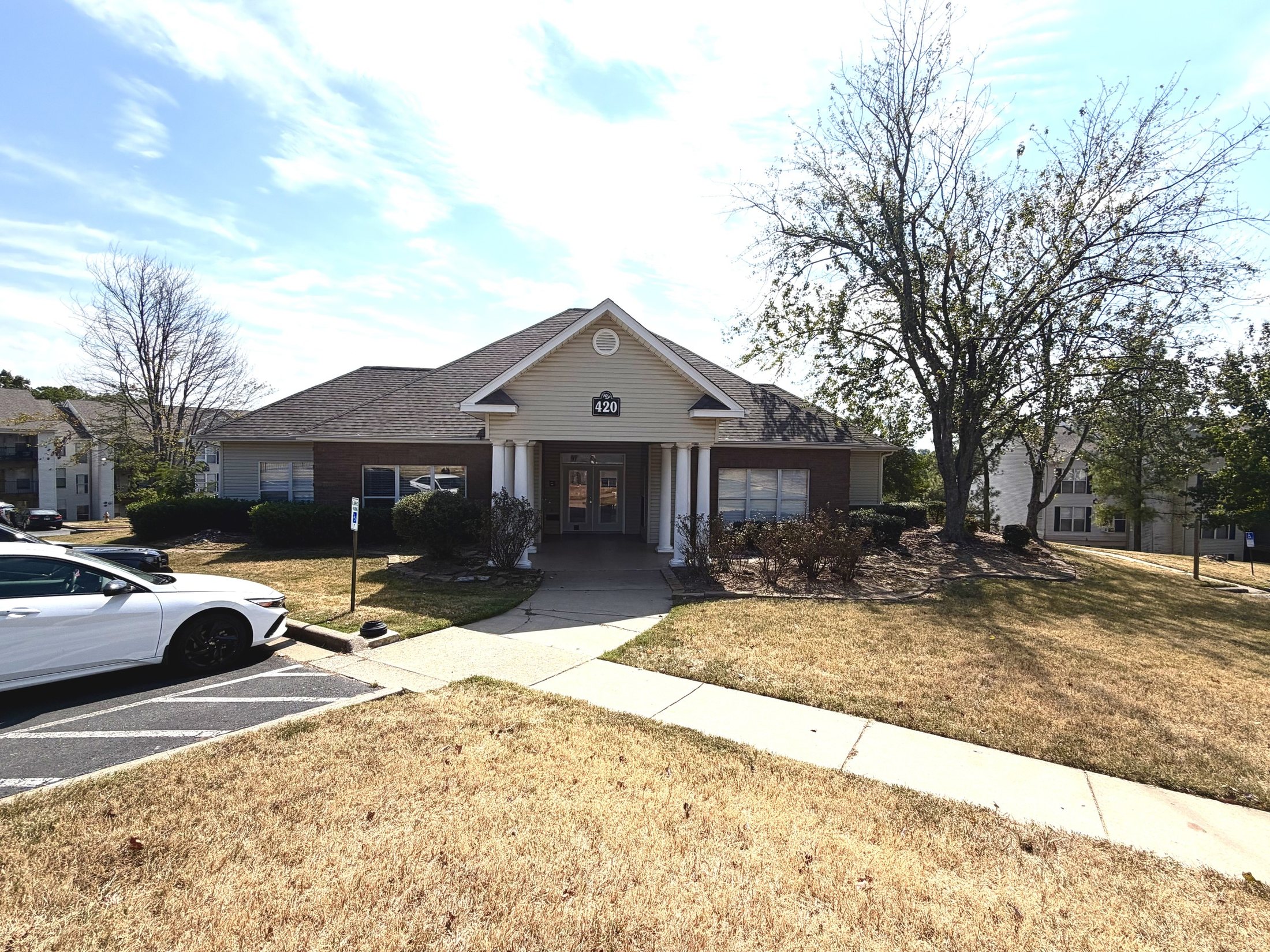 Before: the existing clubhouse exterior with patchy lawn