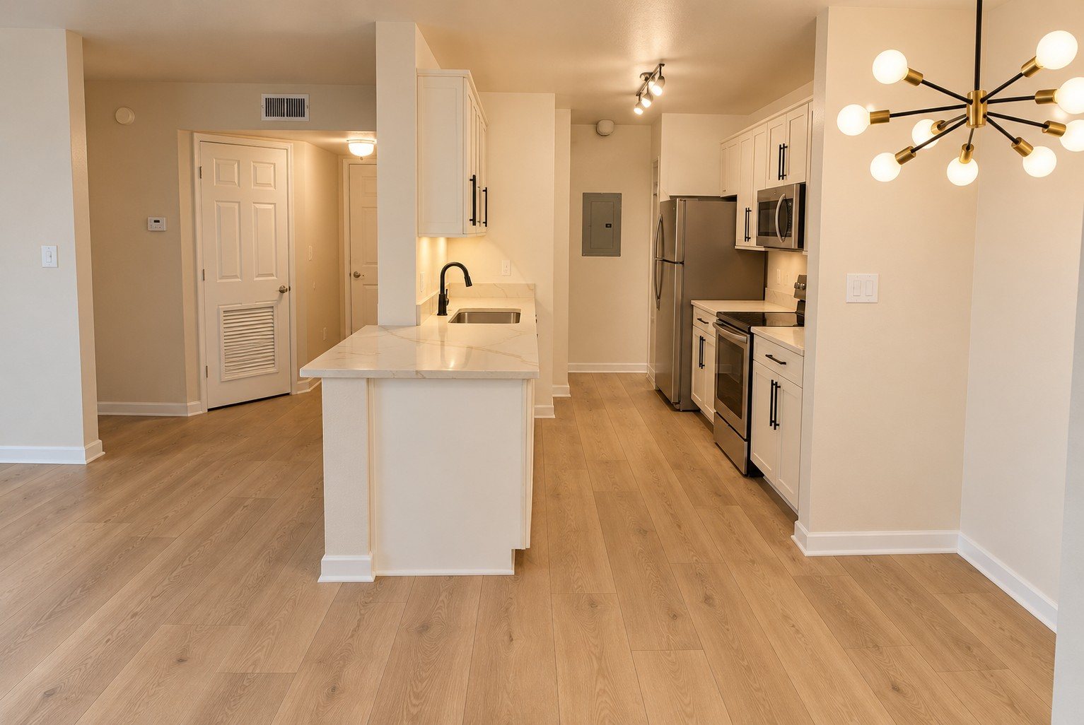 After: a bright kitchen with quartz counters, stainless appliances and light oak flooring
