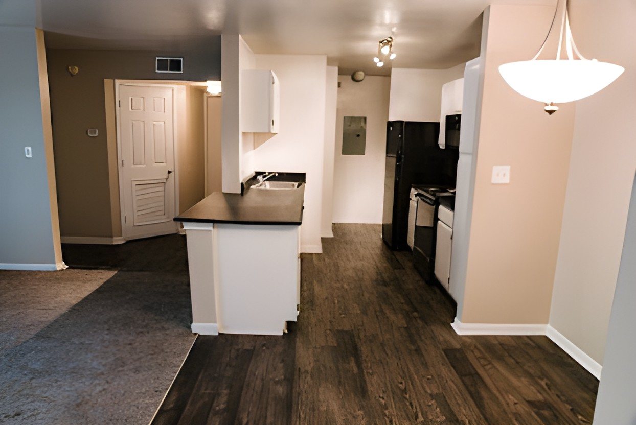 Before: an apartment kitchen with black appliances, dark counters and dark flooring