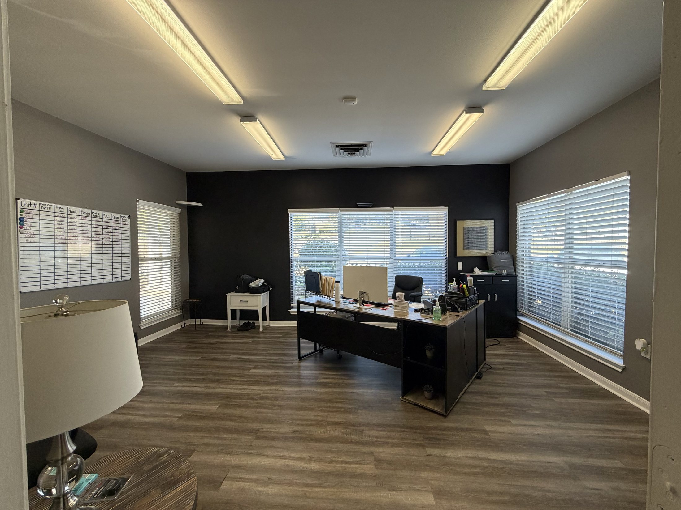 Before: the leasing office with dark accent wall, blinds and fluorescent lighting