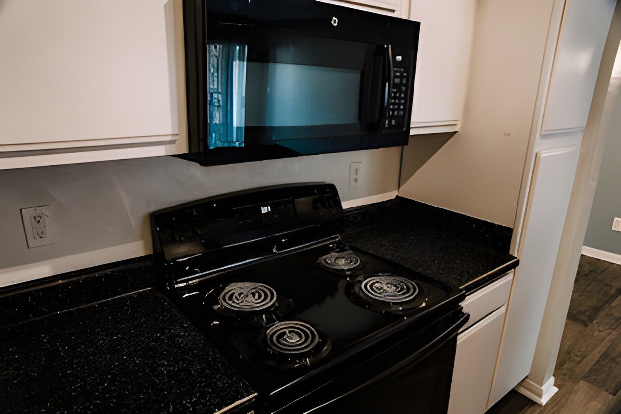 Before: a black range and microwave over speckled black counters