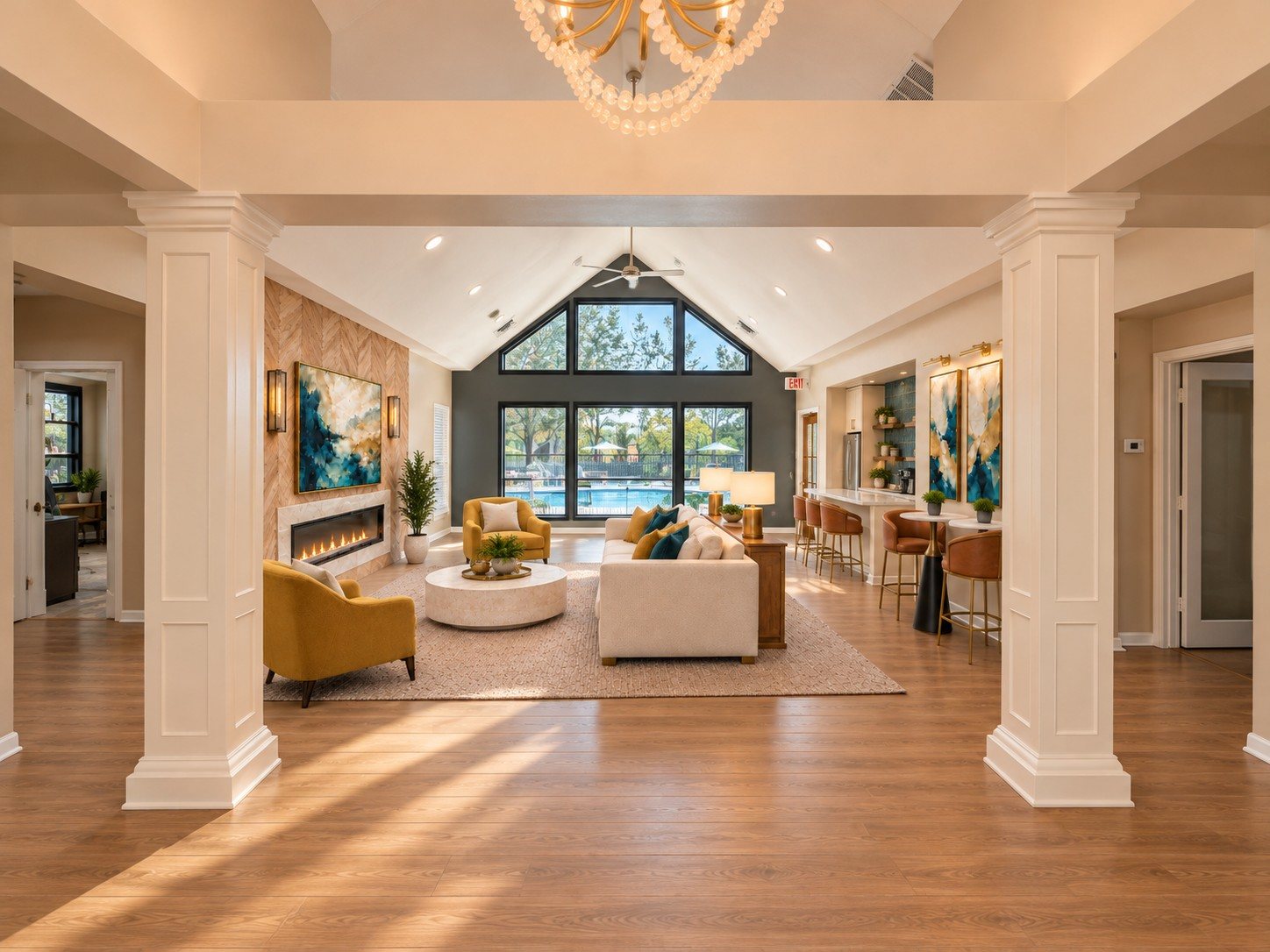 The lounge seen between two white columns, looking through tall windows to the pool