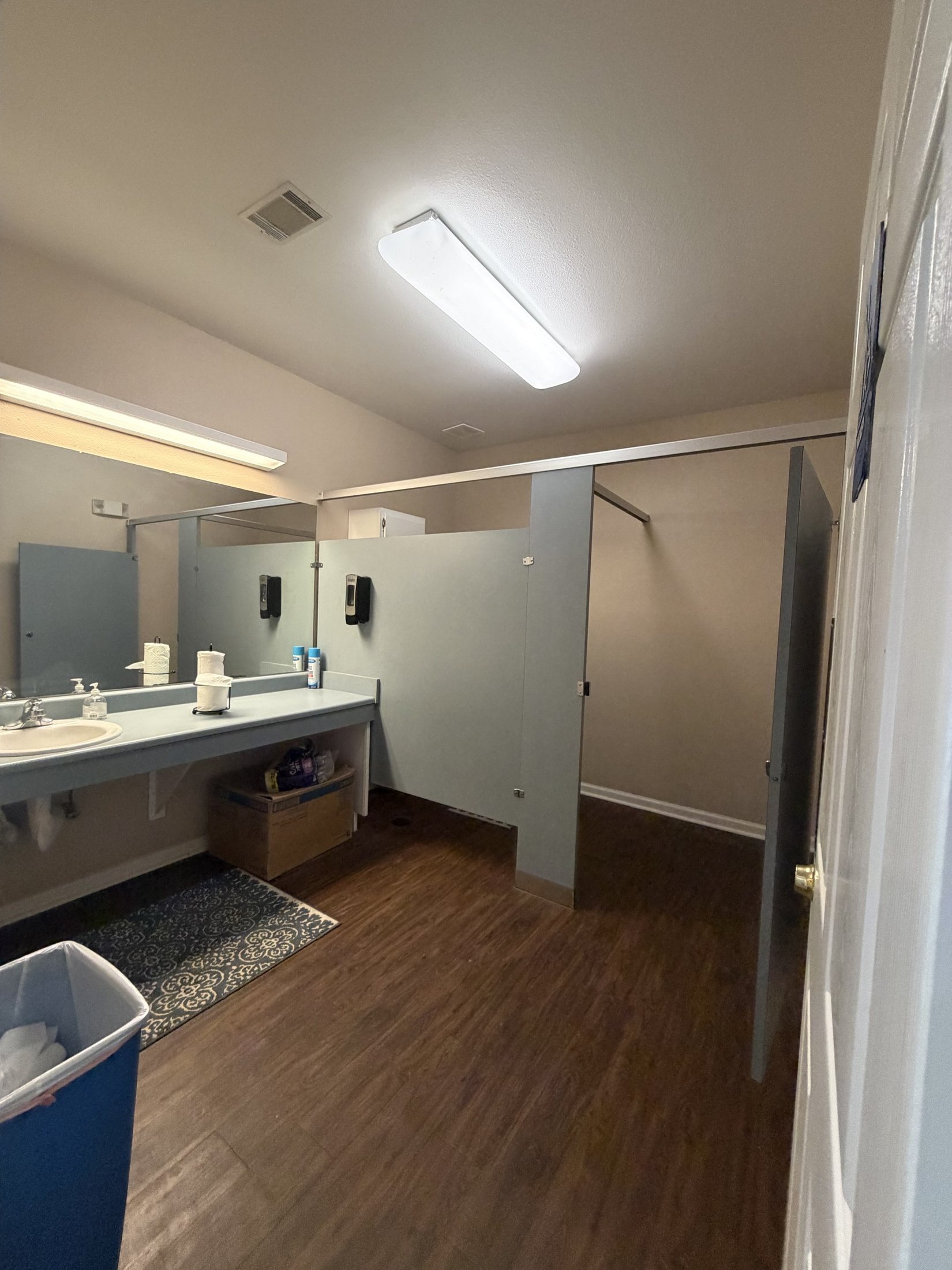 Before: the women’s restroom with grey partitions and a laminate vanity